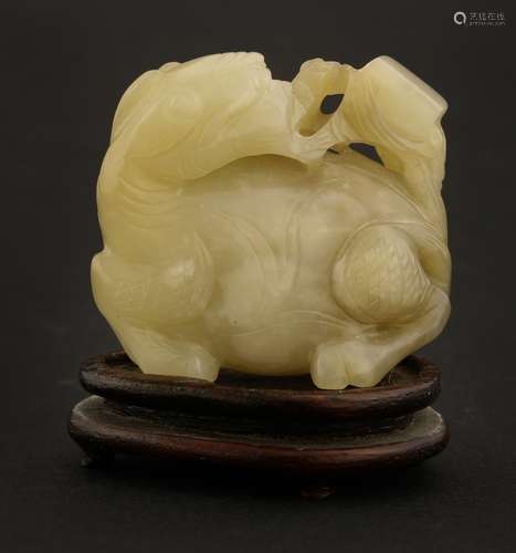 A Chinese jade carving, late Qing dynasty, of a recumbent mythical beast, its head turned to its ...