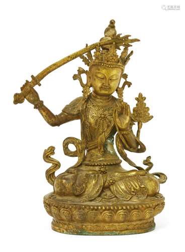 A Chinese bronze bodhisattva, seated cross-legged on a lotus pedestal, wearing elaborate garments ...