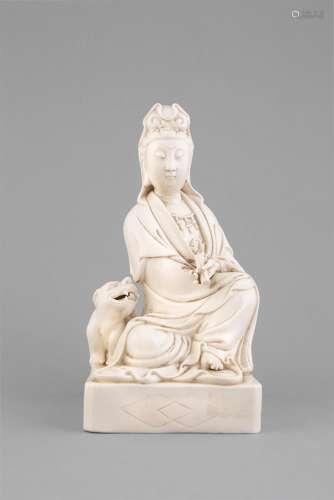 A BLANC DE CHINE GROUP OF A SEATED GUANYIN WITH LION, C.1900, the bodhisattva modelled wearing an