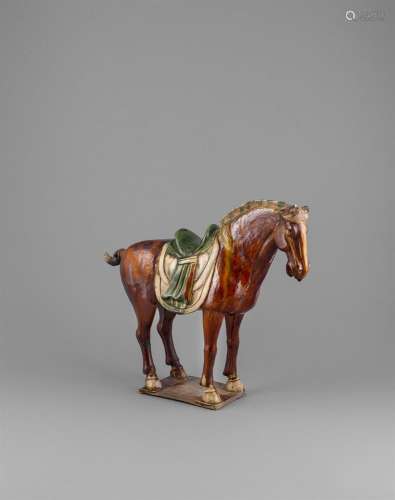 A SANCAI GLAZED BUFF POTTERY MODEL OF A HORSE, standing four square with overlaid saddle in straw