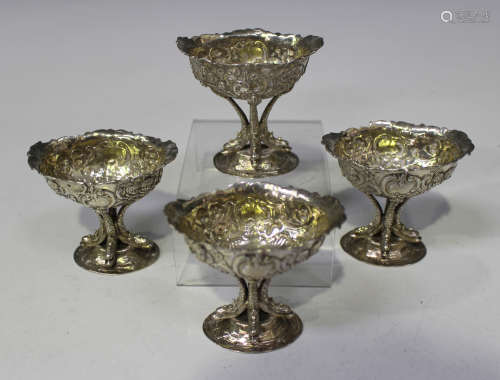 A set of four Edwardian silver salts, each oval bowl decorated in relief with cherub masks and