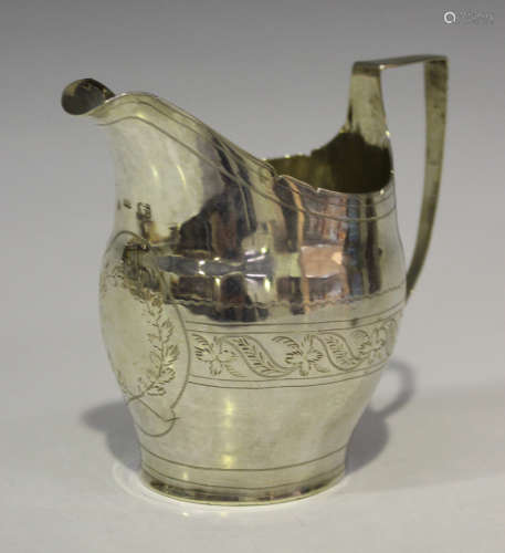 A George III silver oval cream jug, engraved with a band of leaves flanked by an angular handle,