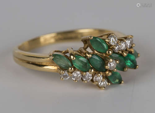 An 18ct gold, emerald and diamond ring in a twist-over design, claw set with marquise shaped