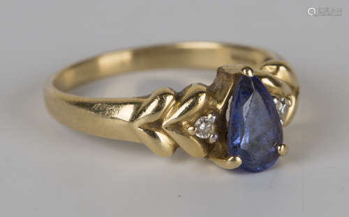 An 18ct gold ring, claw set with a pear shaped blue stone between two circular cut diamonds and