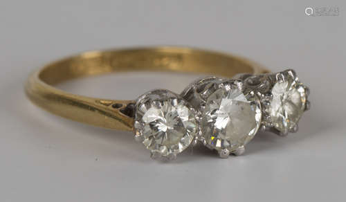 A gold, platinum and diamond three stone ring, claw set with a row of circular cut diamonds with the