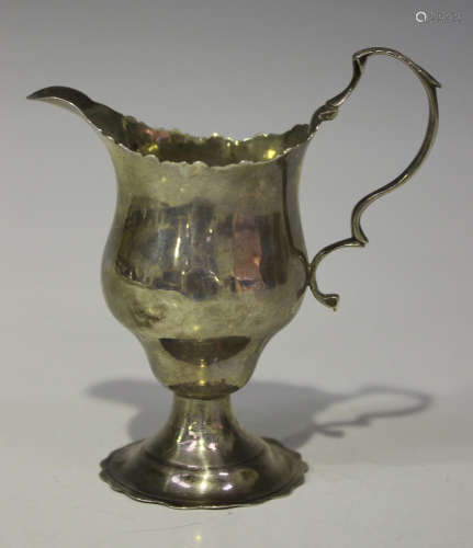 A George III silver cream jug of ogee form with scroll handle, on a petal edged circular foot,