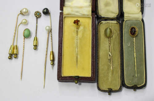 A gold and carbuncle garnet single stone stick pin, a gold and cat's eye single stone stick pin, a