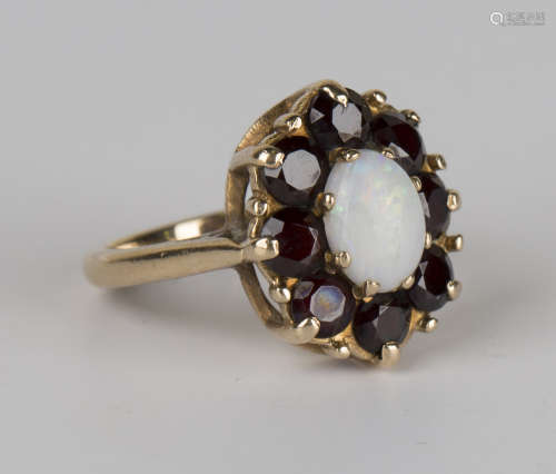A 9ct gold, opal and garnet oval cluster ring, claw set with the oval opal within a surround of