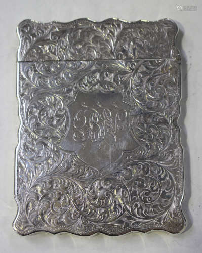 A late Victorian silver rectangular card case with hinged cover, of shaped outline, engraved with