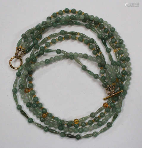 A four row necklace of vari-coloured pale green spherical and tapered baton shaped jade beads, two