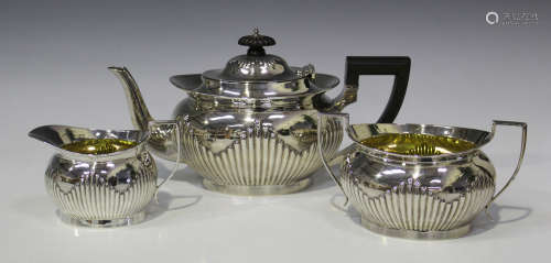 An Edwardian silver three-piece tea set, each piece of half-reeded oval form, comprising teapot,