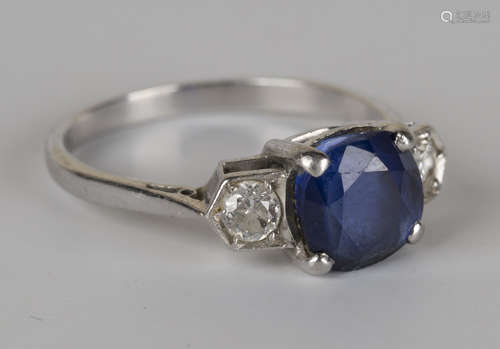 A white gold, platinum, sapphire and diamond three stone ring, claw set with the cushion shaped