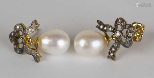 A pair of cultured pearl and diamond pendant earrings, each with a diamond set bow surmount, with