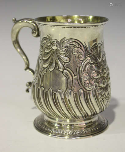 A George III silver mug with foliate capped scroll handle, the low bellied body decorated in