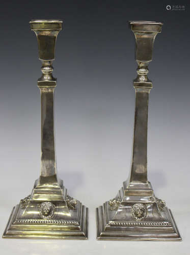 A pair of George V silver candlesticks, each with a detachable nozzle and tapered square column on a
