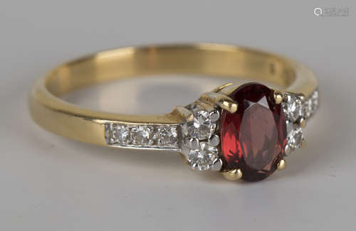 A gold, garnet and diamond ring, claw set with the oval cut garnet to the centre between two pairs