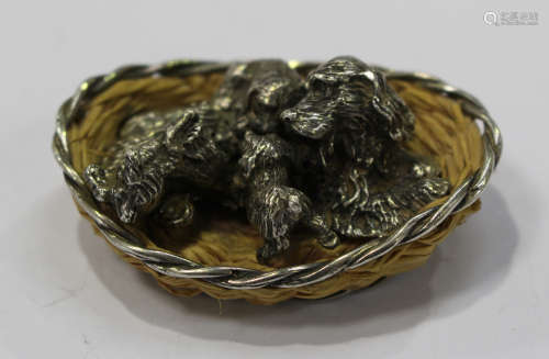 A mid-20th century Spanish cast silver model of a spaniel and three puppies, within a woven basket