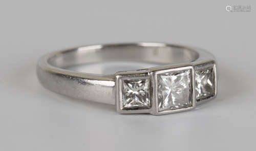 A platinum and diamond three stone ring, mounted with a row of princess cut diamonds with the