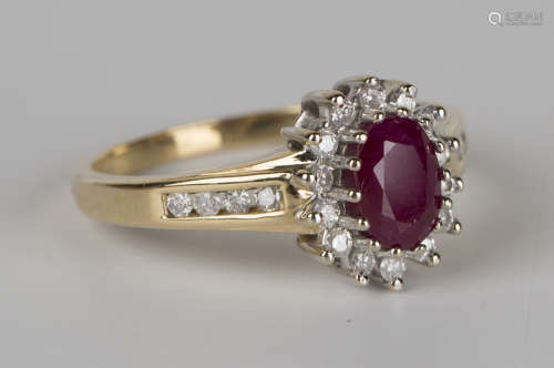 An 18ct gold, ruby and diamond cluster ring, claw set with an oval cut ruby within a surround of