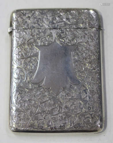 A late Victorian silver rectangular card case with hinged cover, engraved with foliate scrolls,