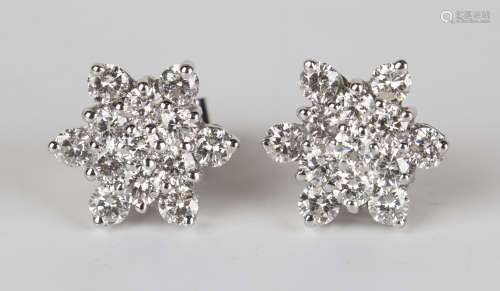 A pair of diamond earrings, each in a flowerhead design, claw set with circular cut diamonds, with
