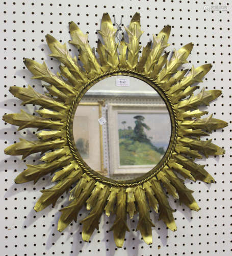 A mid-20th century Chaty Vallauris style gilt painted metal circular wall mirror of flowerhead form,