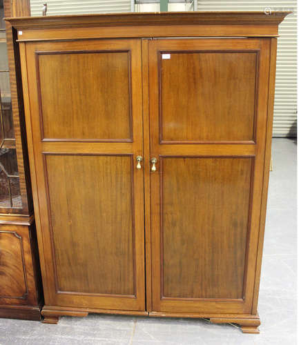 A George V mahogany two-section wardrobe, the moulded pediment above two panel doors, on ogee