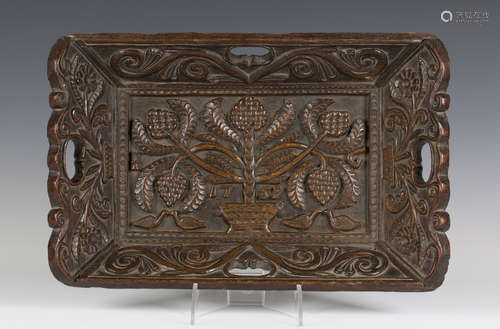 A George II oak rectangular tray, the centre carved in high relief with a stylized plant and four