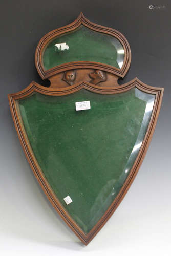 A late Victorian oak framed wall mounted display case of shield form, the two glazed compartments