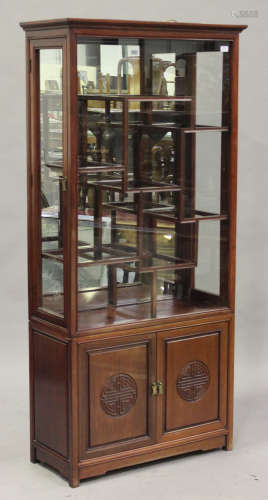 A 20th century Chinese hardwood display cabinet with asymmetric shelves, the mirrored back above a