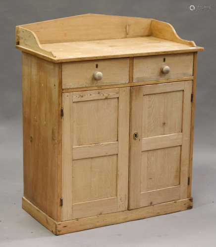 A Victorian pine cabinet, the three-quarter gallery above two short drawers and a cupboard, on a