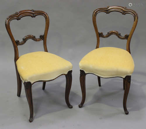 A pair of early Victorian rosewood spoon back dining chairs, the overstuffed seats on carved