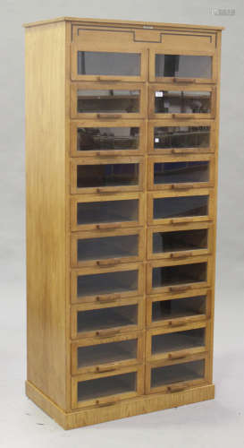 An Art Deco oak haberdashery cabinet by Dudley & Co Ltd, London, fitted with twenty glazed sliding