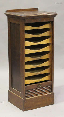 A George V oak filing cabinet, the hinged top above a tambour shutter, on a plinth base, height