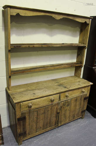 A 19th century and later stripped pine dresser, the shelf back above two drawers and cupboards, on