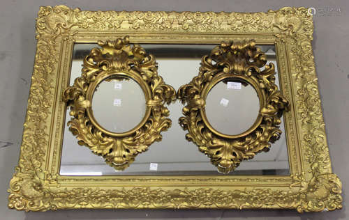 A pair of late 19th century Florentine giltwood oval wall mirrors with carved foliate scrolling