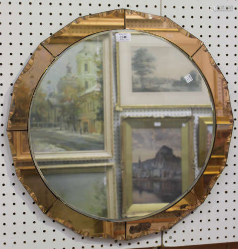 An Art Deco circular wall mirror with a sectional peach tinted surround, diameter 60cm.Buyer’s