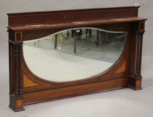 An Edwardian mahogany overmantel mirror, the wide shield shaped bevelled glass within a surround