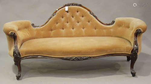 A mid-Victorian walnut showframe salon settee, upholstered in peach velour, raised on carved foliate