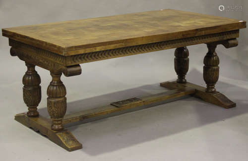 A 20th century French walnut draw-leaf dining table, the parquetry top raised on turned and carved