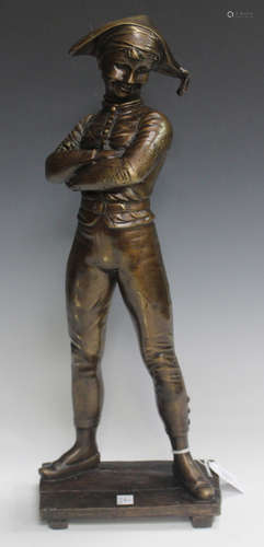 A modern brown patinated cast bronze figure of a standing harlequin wearing a face mask and with his