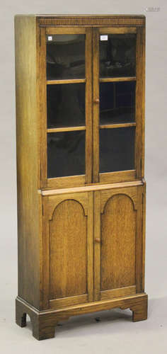 An early 20th century oak glazed bookcase, fitted with a pair of glazed doors above a pair of