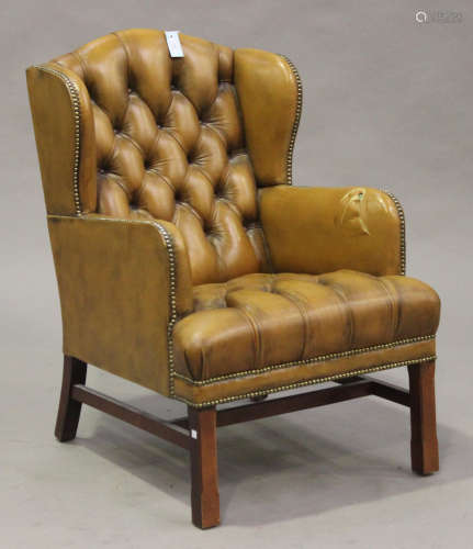 A late 20th century wing back armchair, upholstered in buttoned brown leather, on chamfered block