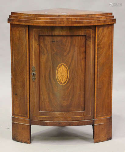 An early 19th century Continental figured mahogany and inlaid bowfront corner cabinet, the stepped