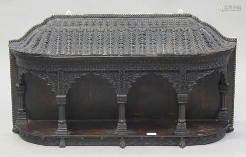 A late 19th century Ceylonese carved hardwood architectural wall shelf, the sloping serpentine top