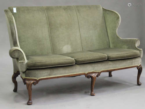 An early 20th century Queen Anne style wing back settee, upholstered in green velour, raised on
