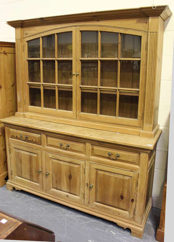 A modern pine kitchen dresser, the glazed cabinet above three drawers and cupboards, on bracket