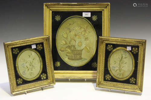 A group of three Regency oval silkwork floral panels, each mounted within a verre églomisé border