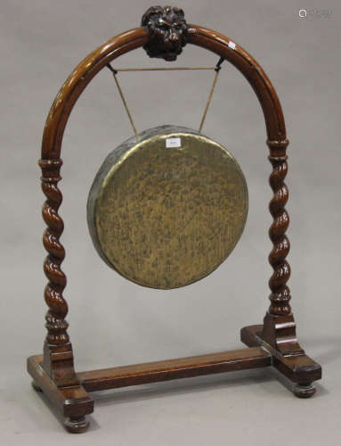 A late Victorian walnut dinner gong stand, carved with a lion's mask, raised on barley twist