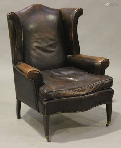 An early 20th century brown leather wing back armchair, on square tapering legs, height 111cm, width